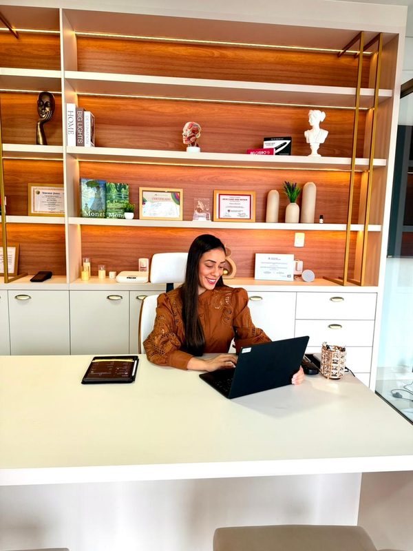 Dra. Joyce Menezes no consultório, atendendo à mesa.